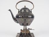 an antique silver teapot on a stand with a handle