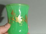 a person holding a green vase with a gold design on it