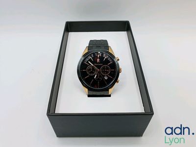 la montre se trouve dans un coffret noir posé sur une surface blanche