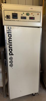 un réfrigérateur blanc posé dans une pièce, à côté d'autres appareils électroménagers
