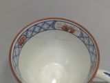 a white cup with a blue and orange design on it