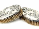 pair of antique silver plated brushes on a white background