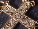 a gold cross on a black cloth with a chain around it