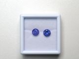 une paire de saphirs bleus dans un écrin blanc posé sur une surface blanche