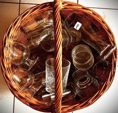 a wicker basket full of empty glassware on a tile floor