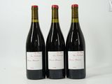 trois bouteilles de vin rouge posées l'une à côté de l'autre sur une surface blanche