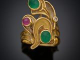 un gros plan d'une bague en or sertie de pierres vertes et roses