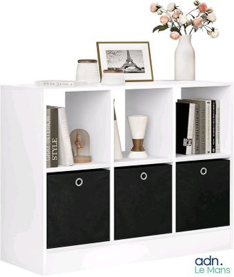 une bibliothèque blanche avec des bacs noirs et un vase rempli de fleurs