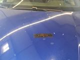a close up of a blue car with a sticker on the hood