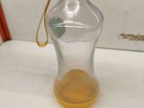 une bouteille d'eau en verre avec une poignée jaune posée sur une table