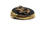 a picture of a gold and black broochle on a white background