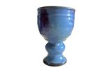 a blue glass cup sitting on a white surface