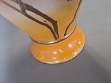 a yellow vase with a bird on it on a table