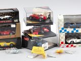 Plusieurs petites voitures sont exposées dans une vitrine posée sur une surface blanche