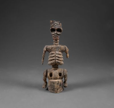 une figurine en bois représentant un squelette assis sur une charrette