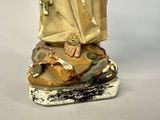 a statue of a man sitting on top of a pile of books