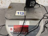 a small electronic scale with a charger on top of it