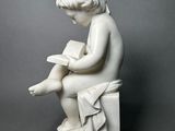 statue of a boy reading a book sitting on a stool