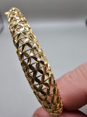 un gros plan sur la main d'une personne tenant un bracelet en or