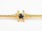 une image représentant une broche en or sertie d'une pierre bleue