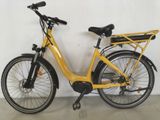 a yellow bicycle parked against a wall with a basket on the back