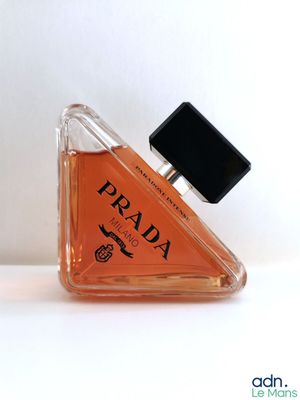 un petit flacon de parfum posé sur une surface blanche