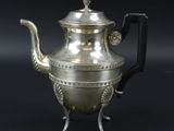 une théière ancienne en argent avec une anse, sur fond noir