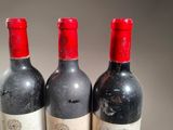 three bottles of red wine sitting on top of a table
