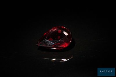 un diamant rouge sur une surface noire dans l'obscurité
