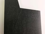 a close up of a piece of black paper on a white surface