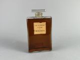 l'image d'un flacon de parfum posé sur une surface blanche