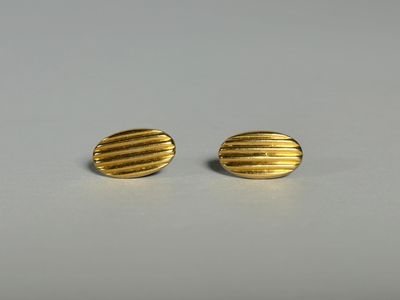 une paire de boucles d'oreilles en or sur une surface blanche