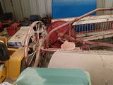 a pile of junk in a garage with a tractor in the background