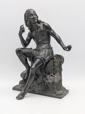 une statue représentant un homme assis sur un rocher, une cigarette à la main