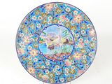 une assiette bleue sur laquelle est représenté un oiseau et des fleurs
