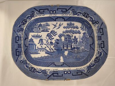 blue and white china platter with a landscape scene on it
