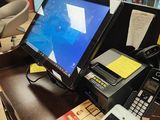 a desk with a monitor, keyboard, phone, and other items on it