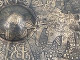 a silver plate with a design on it on a table