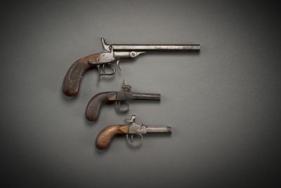 three old revolvers hanging from a hook on a wall