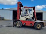 a red forklift truck parked in front of a building