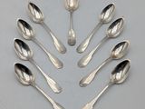 six cuillères en argent disposées en cercle sur une surface grise