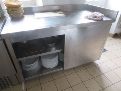 un plan de travail en acier inoxydable sur lequel sont posées des assiettes, dans une cuisine