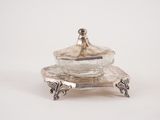 un plat en argent ancien surmonté d'un bol en verre