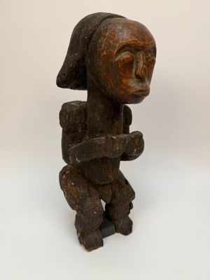 une vieille statue en bois représentant une femme coiffée d'un chapeau