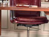 a desk with a chair and bookshelf in the background