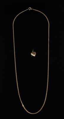 un collier en or avec un pendentif en forme de cœur sur fond noir