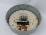 a small battery in a metal container on a white surface