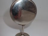 a silver flaskt on a stand on a white surface