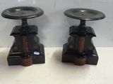 deux bougeoirs noirs posés sur une table blanche