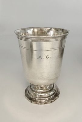 une coupe ancienne en argent posée sur un socle, sur fond blanc